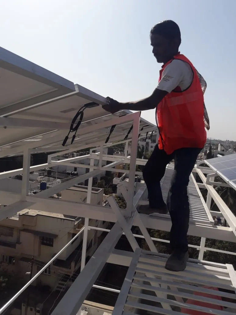 Engineer inspecting solar panel wiring and inverter setup at a commercial site